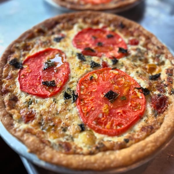 Close-up of a southern tomato pie with sliced tomatoes and herbs on a flaky crust.